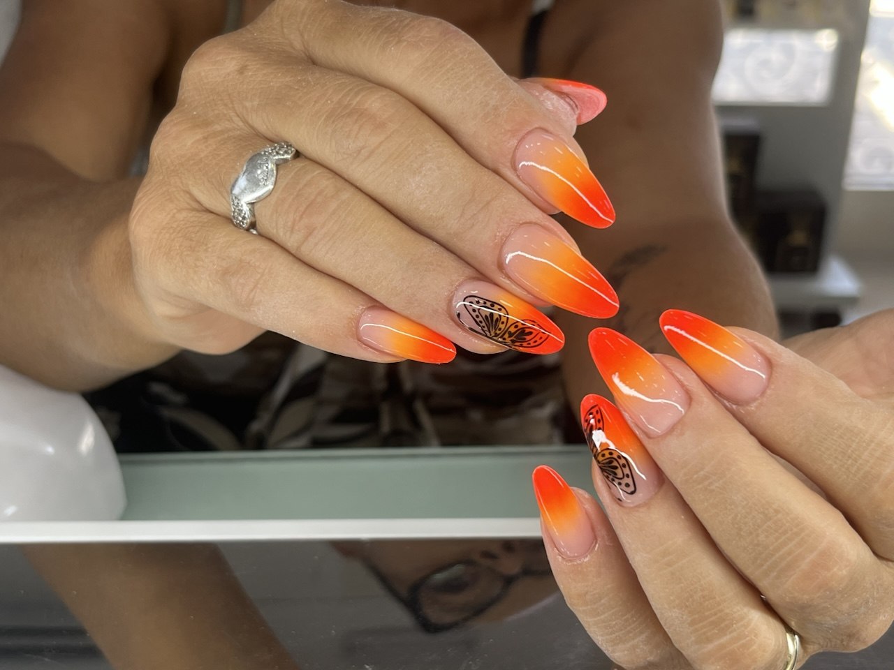Unghie sfumate arancio con farfalle disegnate a mano